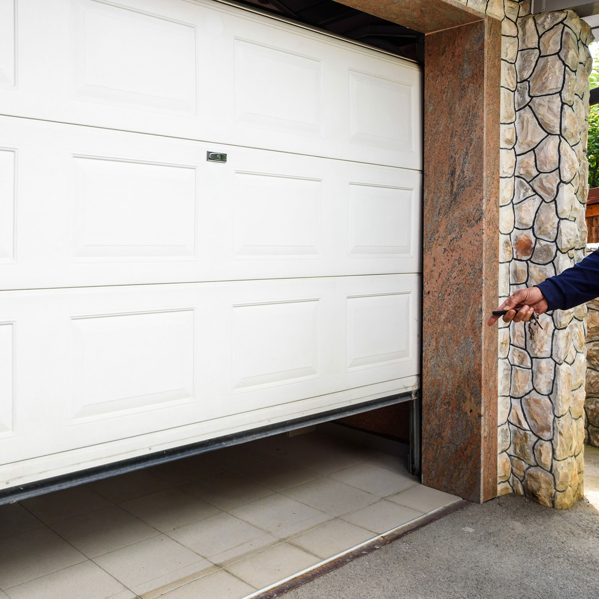 Porta del garage con sistema di apertura, parzialmente aperta, persona tiene telecomando in mano