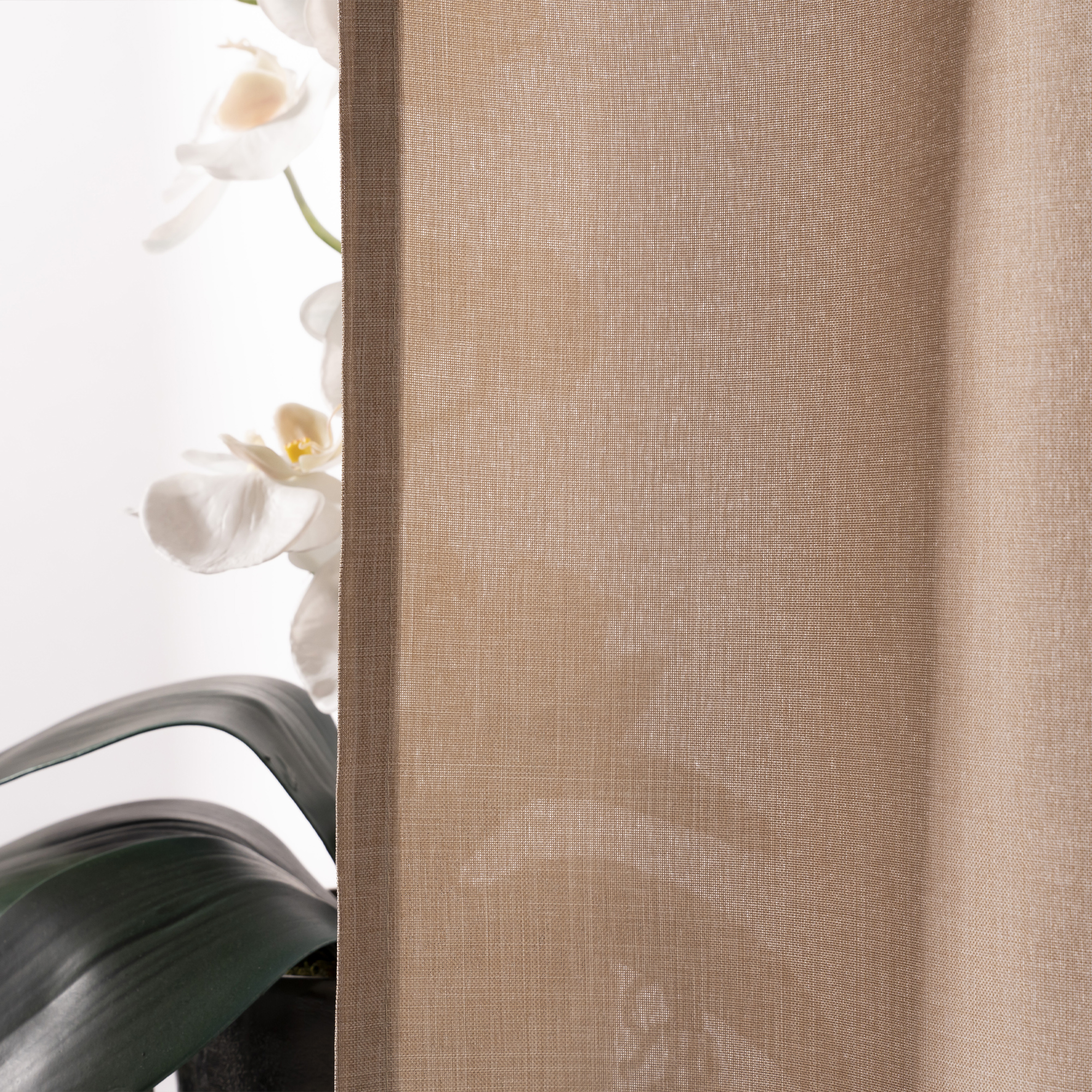 Dettaglio di una tenda con tessuto trasparente, sullo sfondo una pianta con fiori