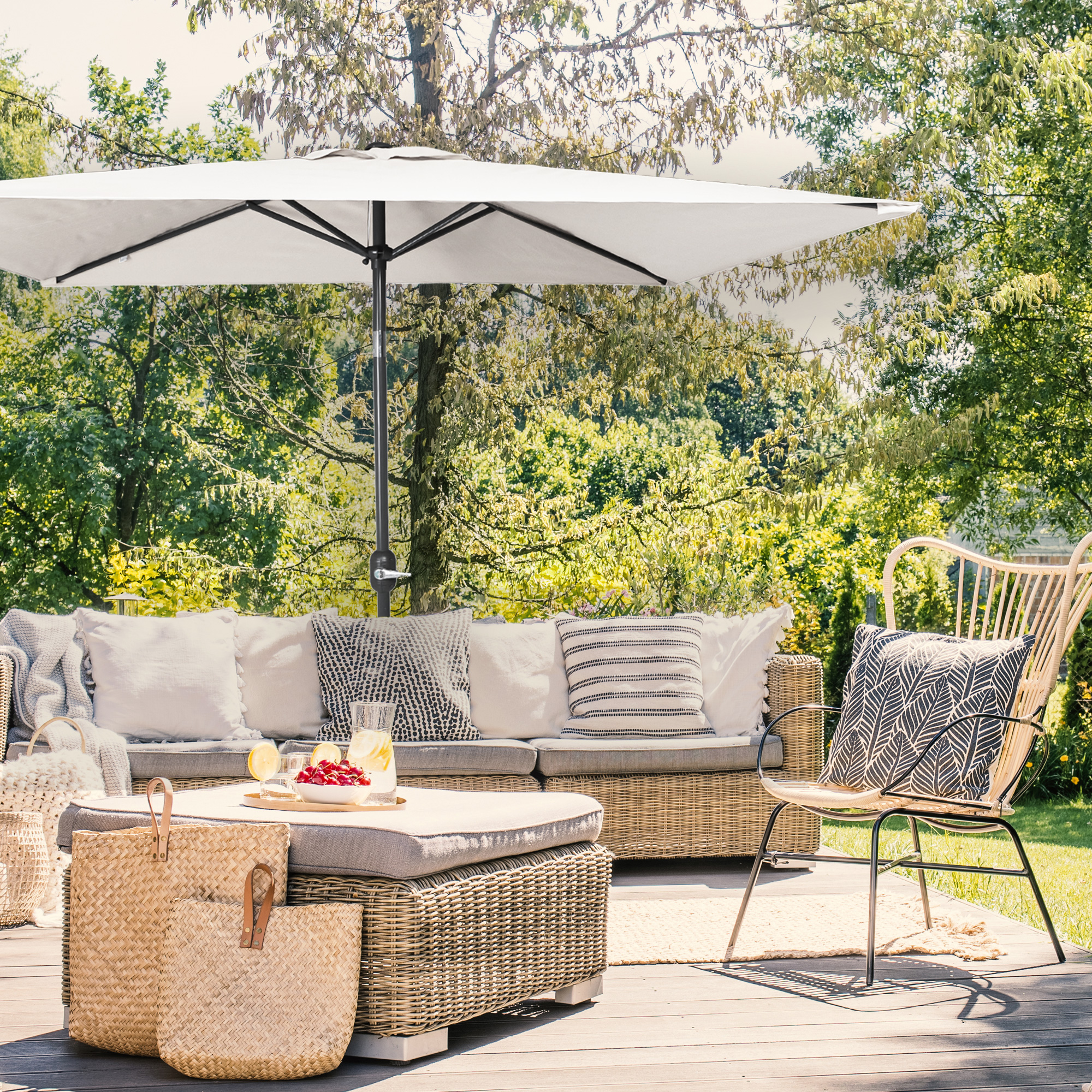 Piccolo ombrellone pieghevole sopra una terrazza con mobili da giardino e piante sullo sfondo