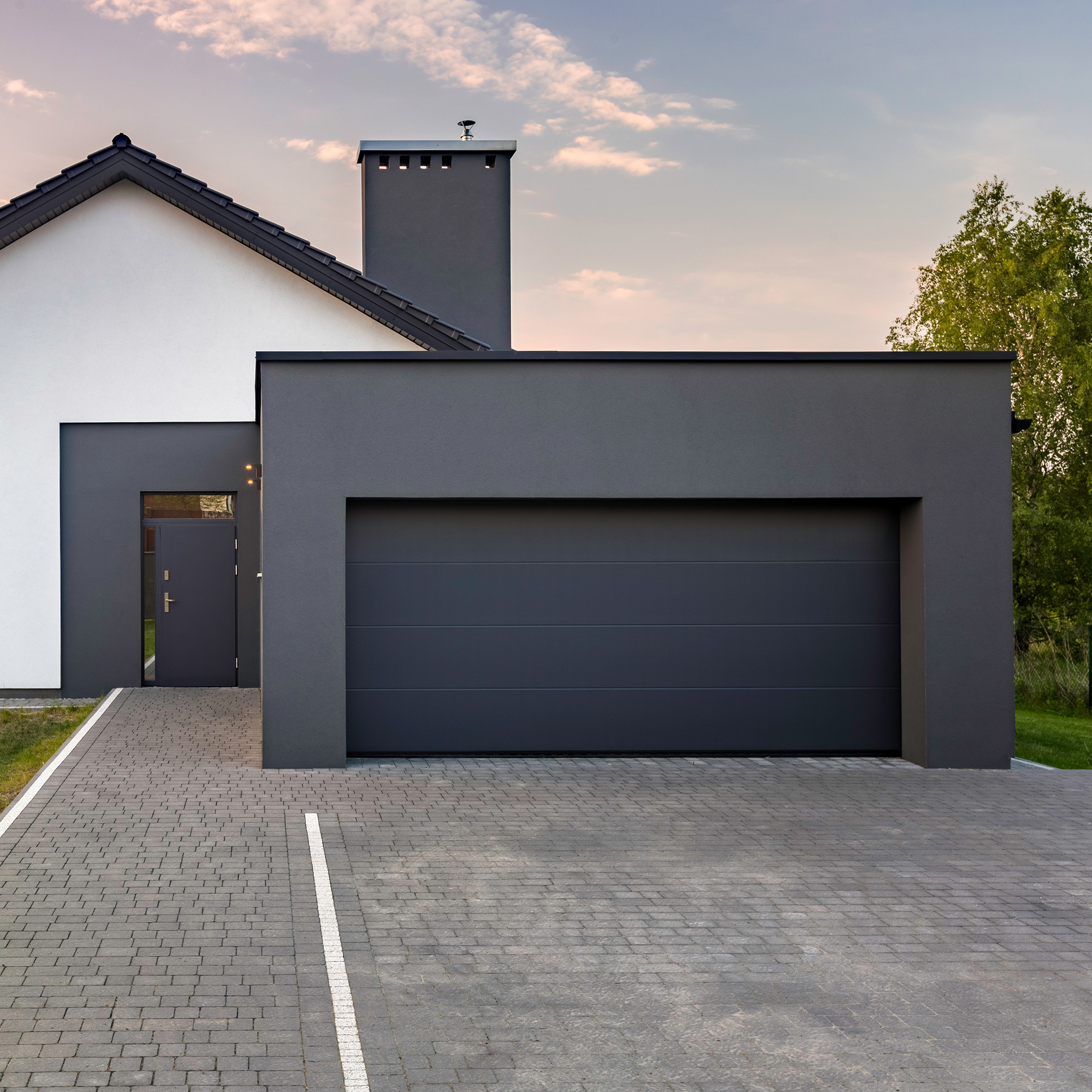 Una casa moderna con grande garage e vialetto pavimentato