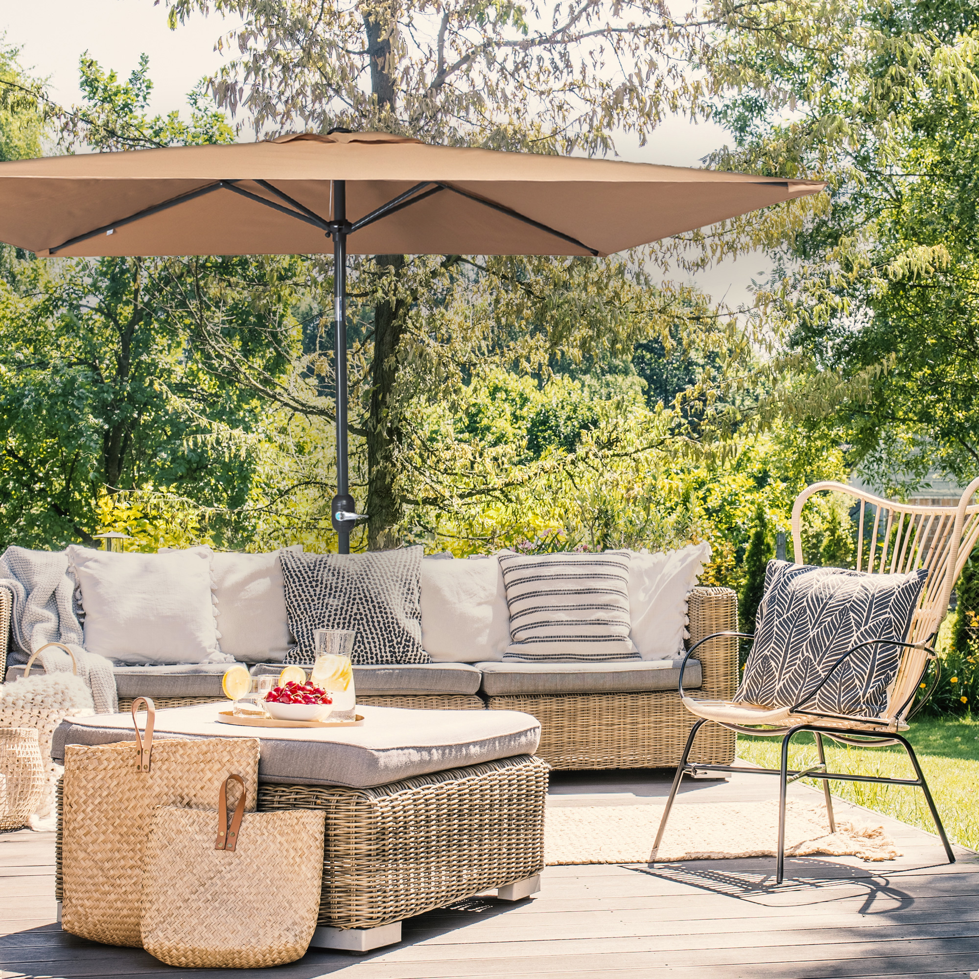 Piccolo ombrellone pieghevole sopra una terrazza con mobili da giardino e piante sullo sfondo
