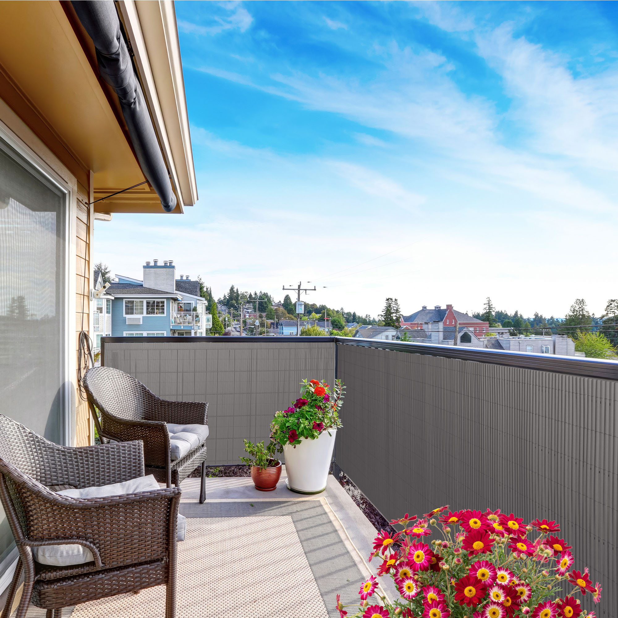 Balcone con rivestimento in bambù, due sedie e piante in vasi