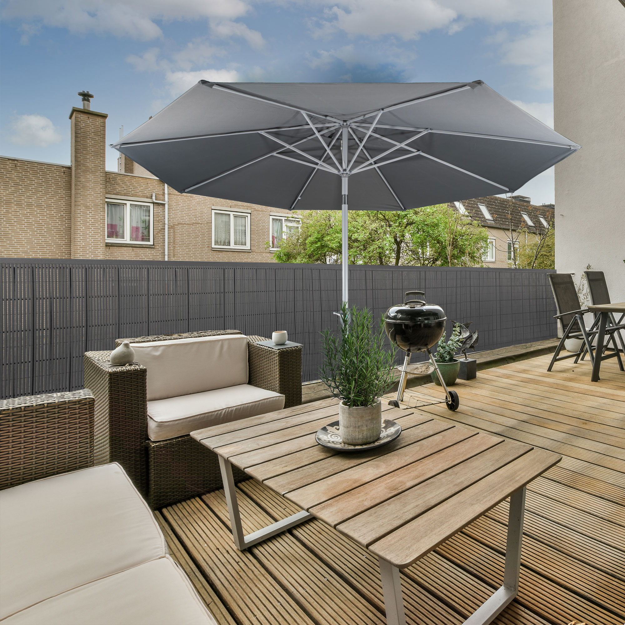 Terrazza con tappeto per la privacy in bambù, mobili da giardino e ombrellone