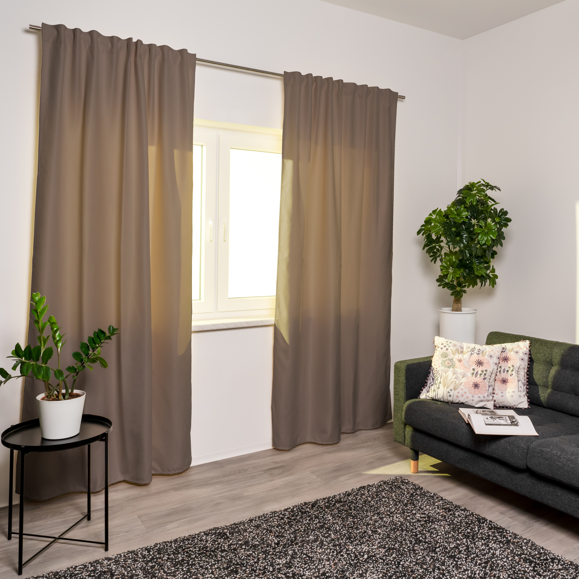 Tenda termica con nastro combinato alla finestra in un soggiorno moderno con piante e divano