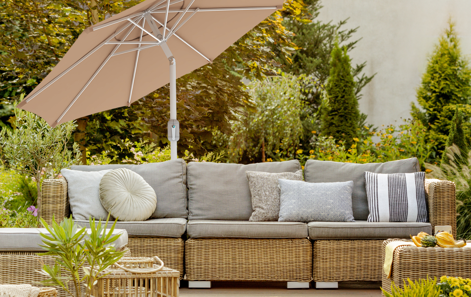 Terrazza con divano in rattan e ombrellone interpara in ambiente giardino
