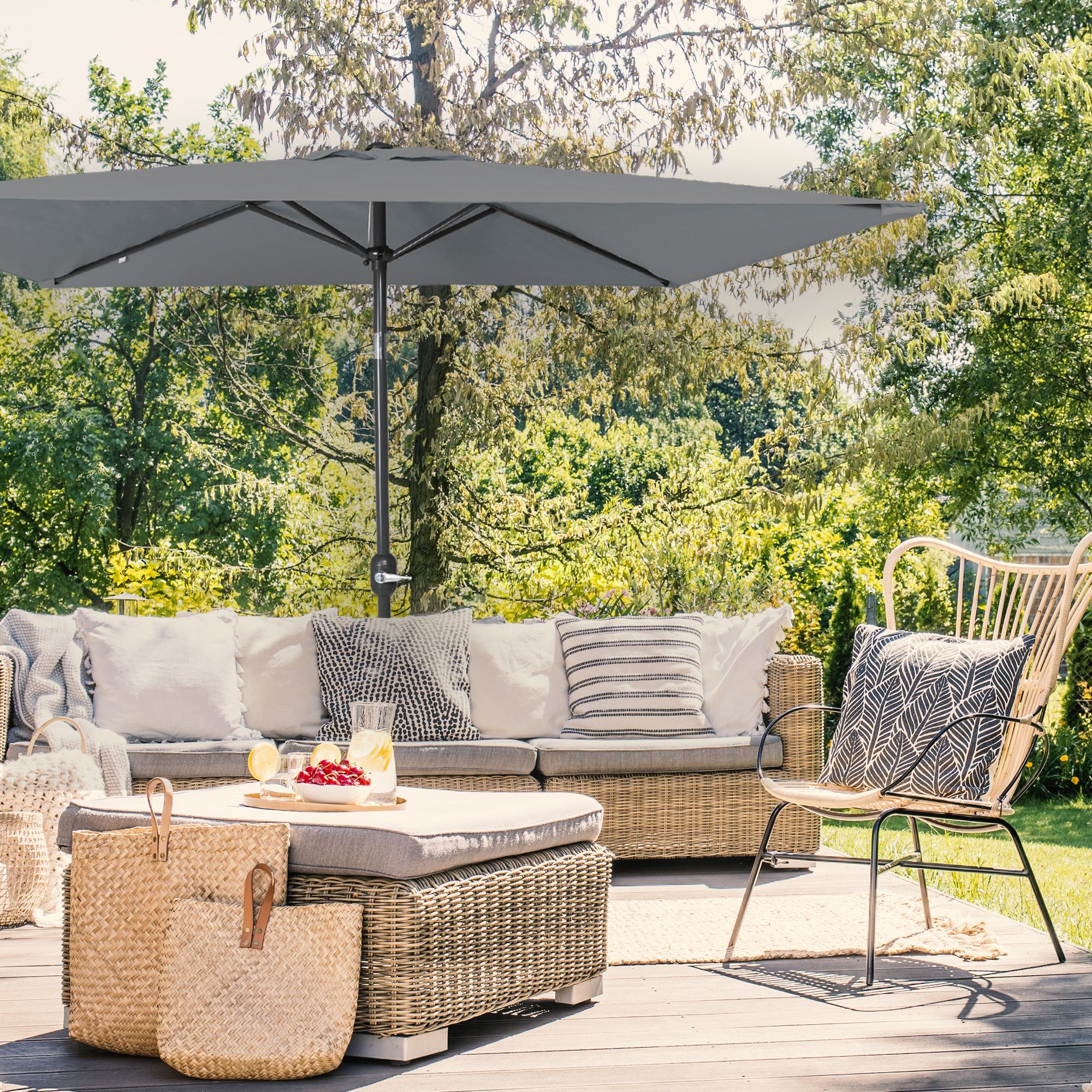 Piccolo ombrellone pieghevole sopra una terrazza con mobili da giardino e piante sullo sfondo