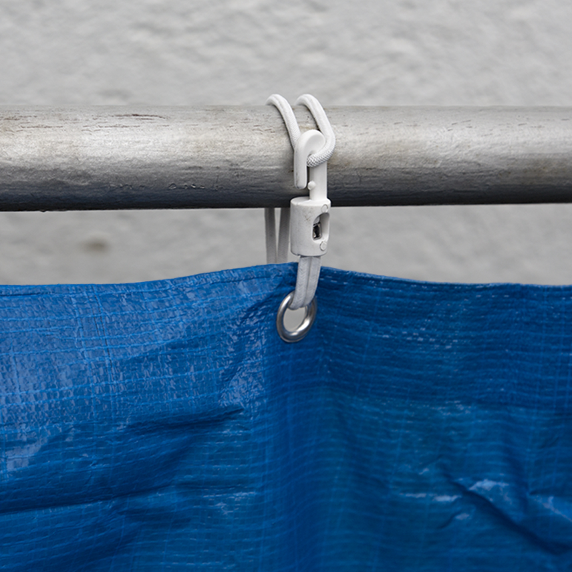 Cinghia elastica con gancio in plastica fissata a un'asta, tiene il telo con occhiello